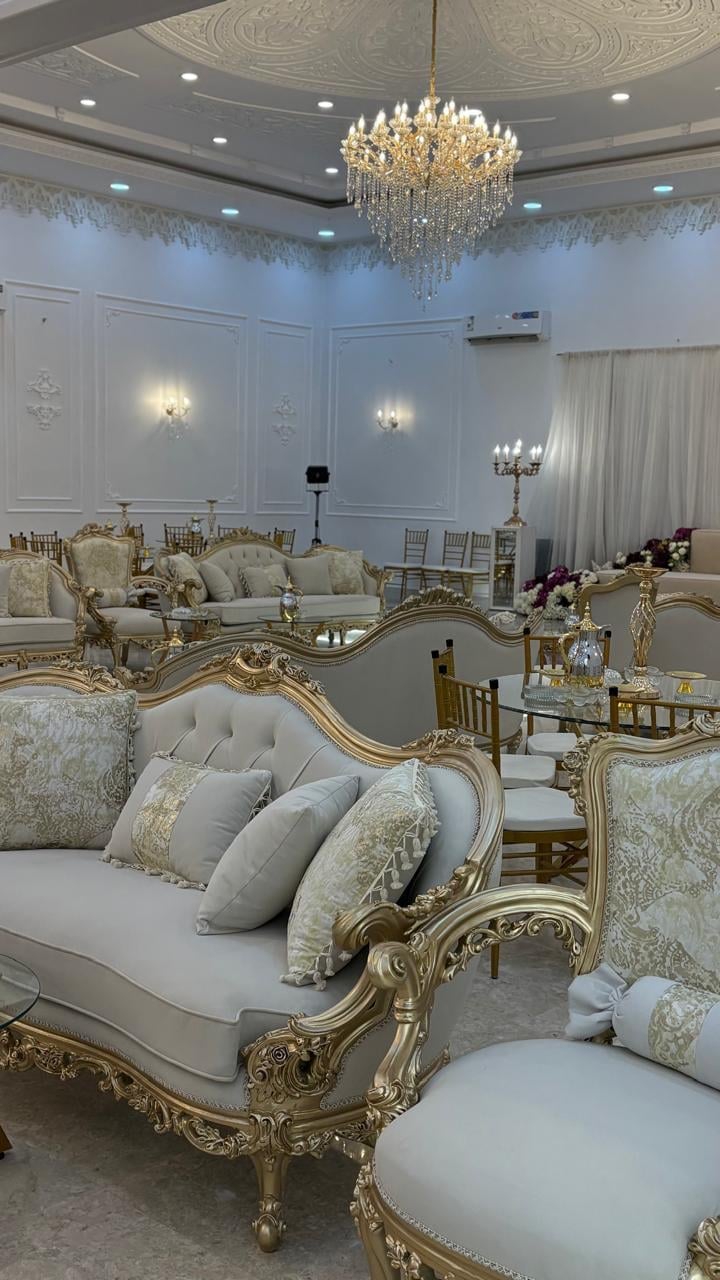 Luxurious bridal salon interior with ornate gold-trimmed furniture, crystal chandelier, and elegant white and gold decor
