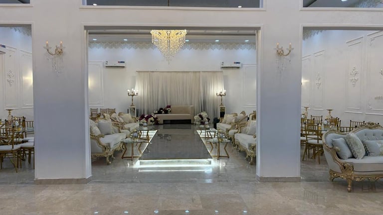 Elegant white ballroom with grand chandelier, ornate seating, and draped curtains opening to polished marble floors