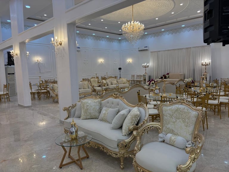 Elegant event hall with ornate gold and white furniture, crystal chandelier, and large windows in bright, modern venue