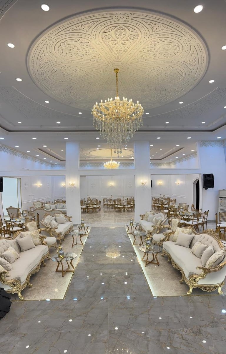 Luxurious banquet hall with ornate ceiling medallion, crystal chandelier, cream seating arrangement, and polished marble floors